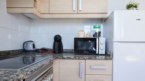 Una cocina compacta con estufa integrada, microondas y cafetera.