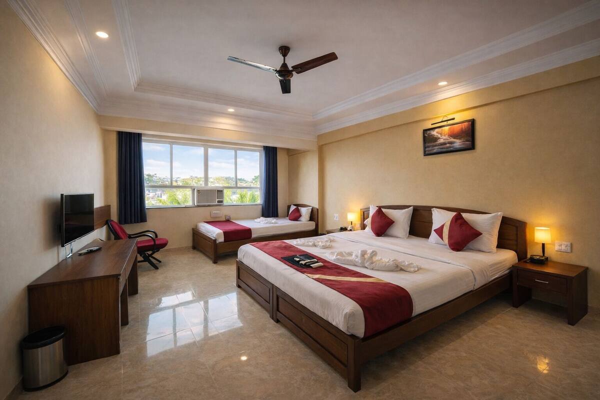 A hotel room with a large bed, a desk, a chair, a TV, and a ceiling fan.