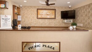 Ein Empfangsbereich mit einem Schild, das "PICNIC PLAZA" zeigt, einem Wandfernseher und einem Deckenventilator.