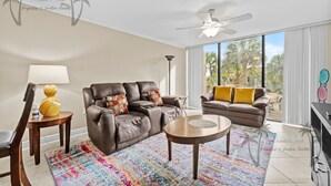 A spacious living room with two leather sofas, a coffee table, and a colorful rug. - Ocean Club Villa D-206 | Your Coastal Paradise Awaits! (Biloxi)