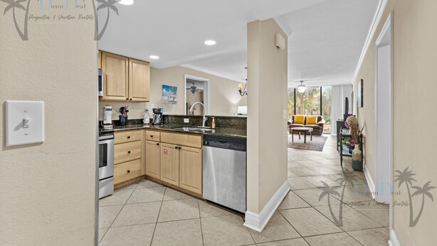 A modern kitchen with wooden cabinets, stainless steel appliances, and a large island. - Ocean Club Villa D-206 | Your Coastal Paradise Awaits! (Biloxi)