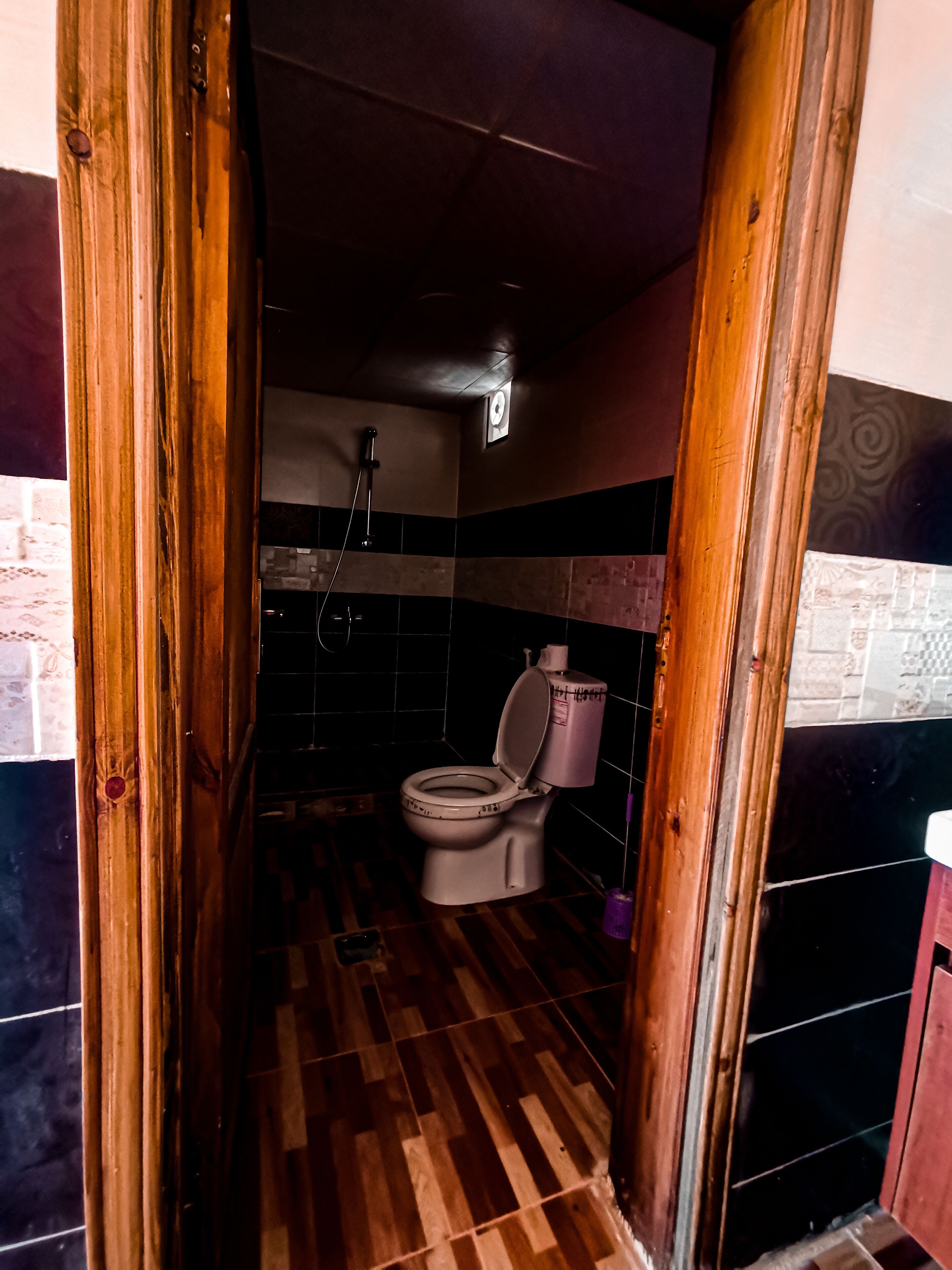 Un baño con inodoro, ducha y piso de madera.