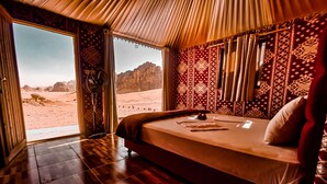 Una habitación con cama, ventilador y vistas a un paisaje desértico.