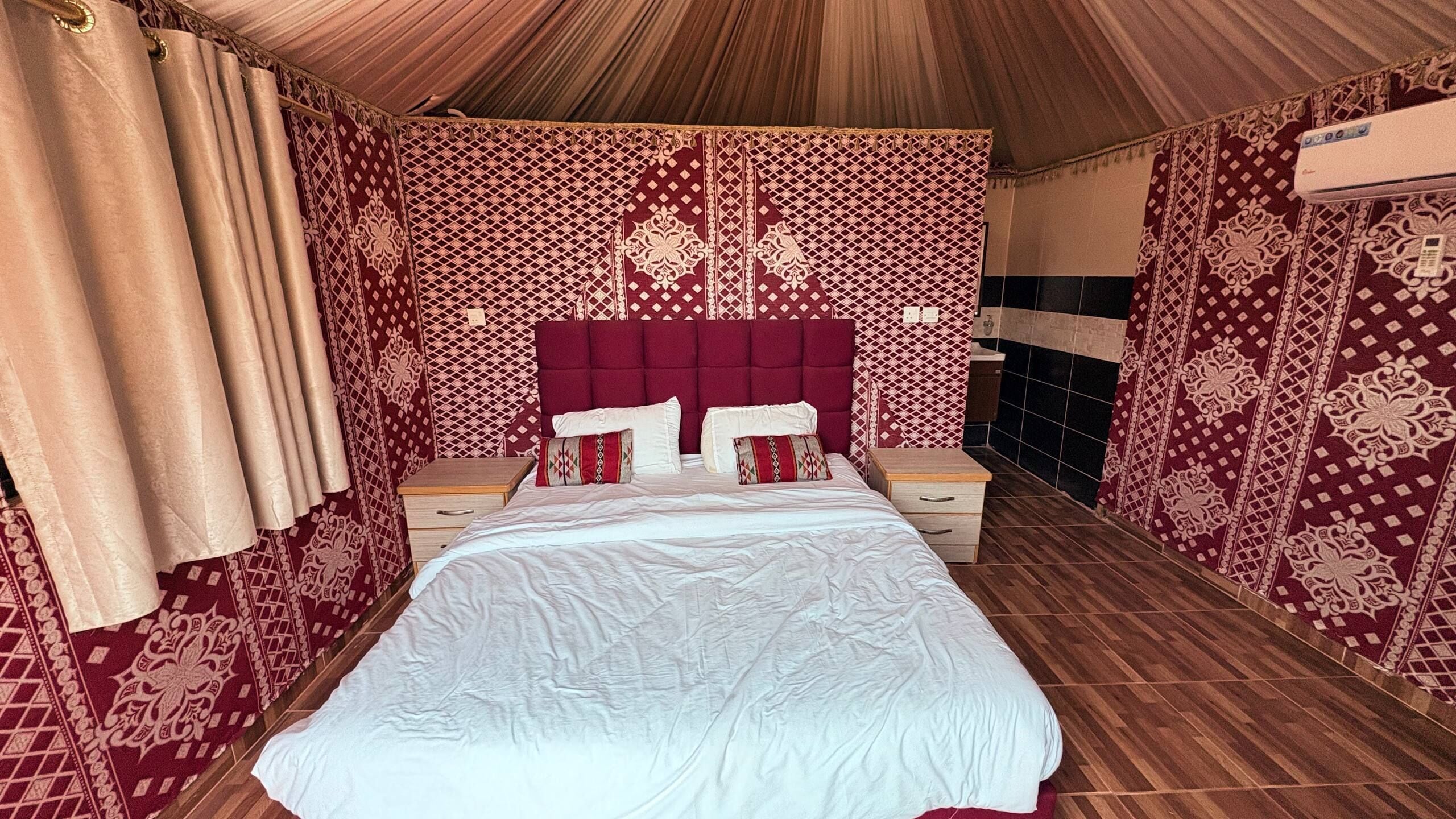 A room with a bed, a nightstand, a dresser, and patterned walls.