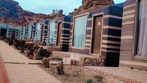 Una hilera de caravanas con paredes exteriores a rayas y ventanas, con montañas al fondo.