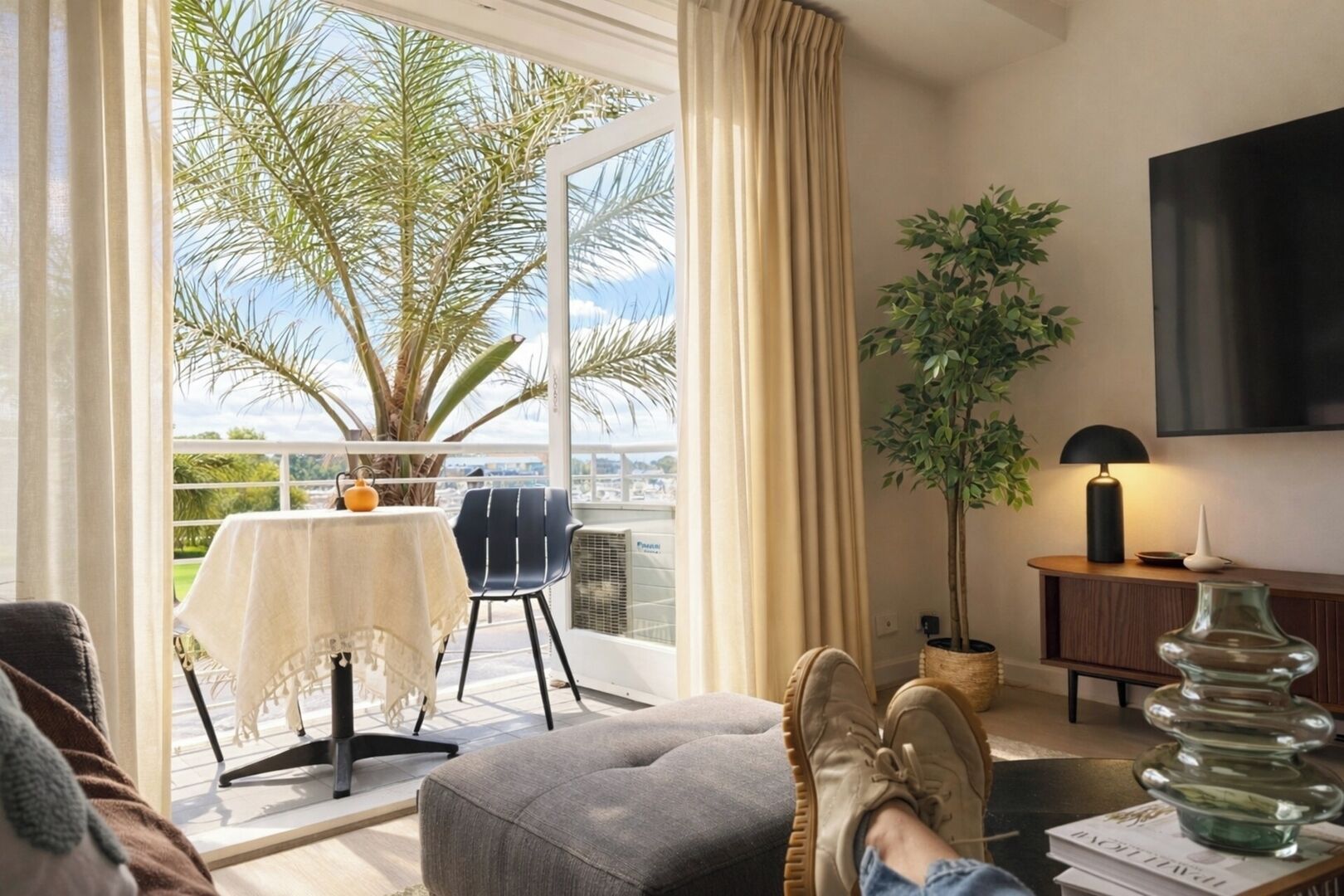 A balcony with a table, chair, and a potted plant.
