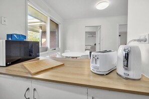 Una cocina moderna con microondas, tostadora y tabla de cortar de madera.