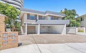A modern building with a covered parking area, a brick mailbox, and a gated entrance. - Sunny, Stylish Island Stay Minutes from Surfers (Surfers Paradise)