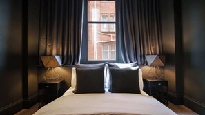 Ein Hotelzimmer mit einem großen Bett, zwei Nachttischen mit Lampen und einem Fenster mit Vorhängen.