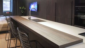 Eine moderne Küche mit einer langen Arbeitsplatte, einem Spülbecken und Barhocker.