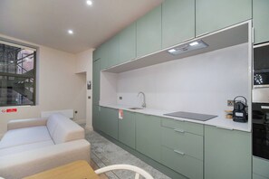 Una cucina moderna con mobili verdi, un piano di lavoro bianco e un forno integrato.
