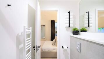 Un bagno moderno con un lavandino bianco, uno specchio e un water.