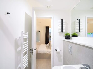 Ein modernes Badezimmer mit einem weißen Waschbecken, einem Spiegel und einer Toilette.