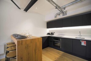 Eine moderne Küche mit einer Holzauslage, schwarzen Schränken und Edelstahlgeräten.
