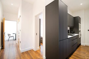 A modern kitchen with dark cabinetry and a wooden floor. - Smithfield | The Heim (Greater Manchester)