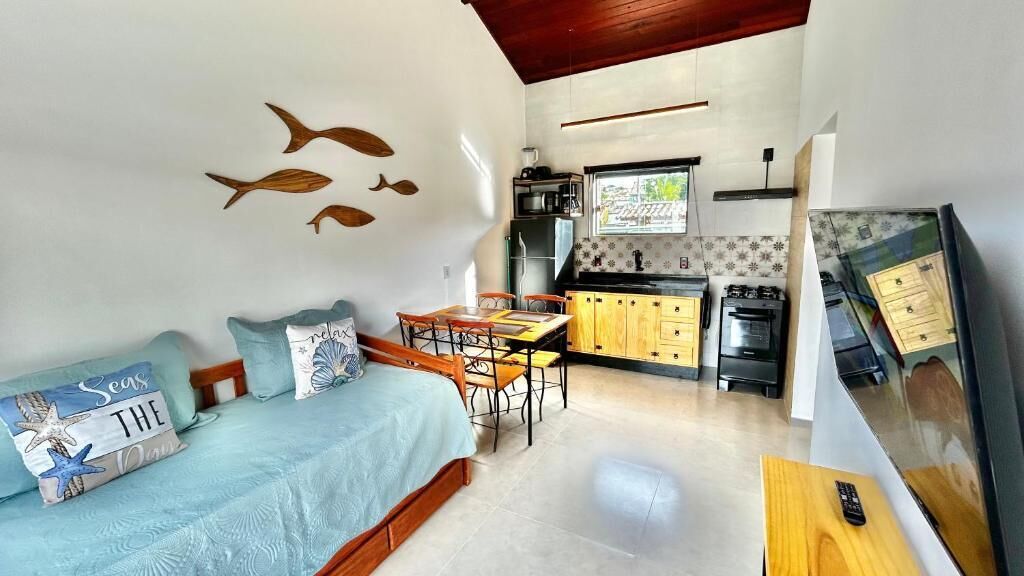 Un espacio habitable compacto con cama, zona de comedor y kitchenette.