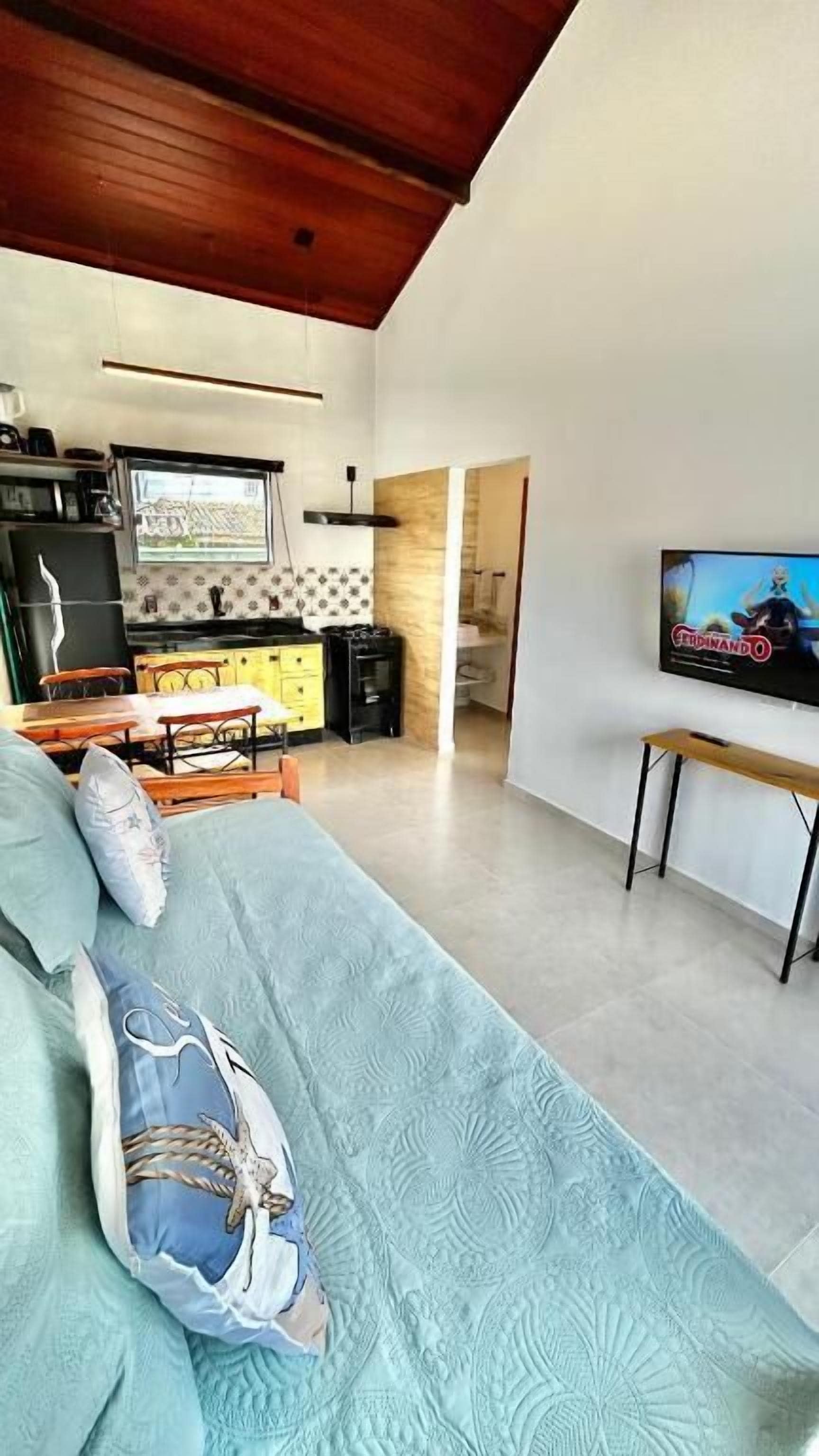 A modern living room with a sofa, a TV, and a kitchen area in the background.