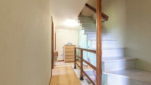 Un corridoio con ringhiera in legno, un termosifone e una scala con gradini bianchi.