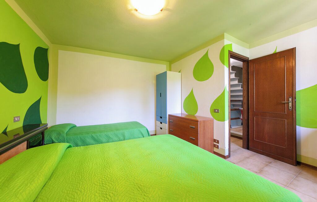 A room with two beds, a wooden wardrobe, a desk, and a staircase leading to an upper level.
