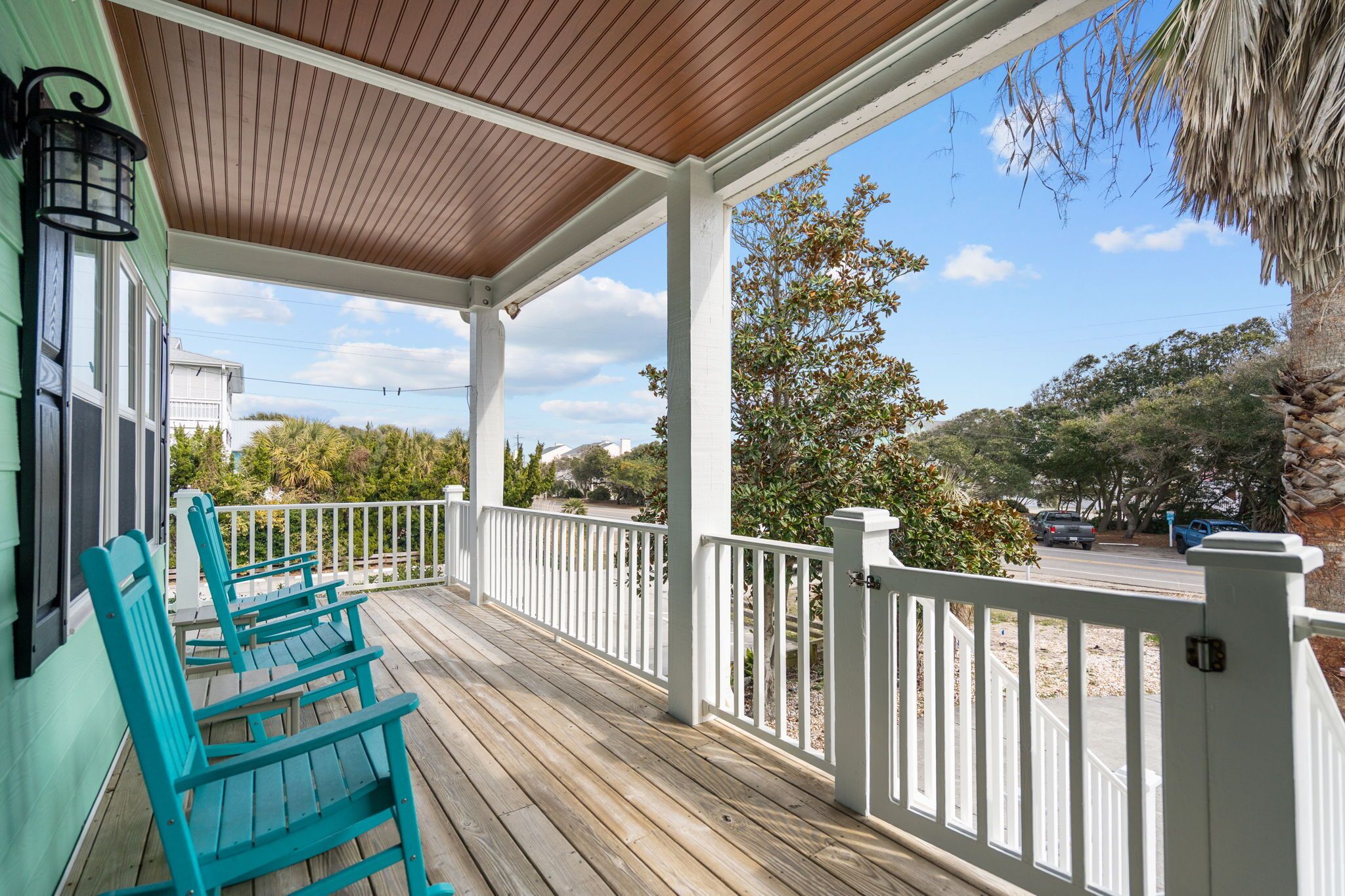 A covered porch with wooden railings and two green chairs.
