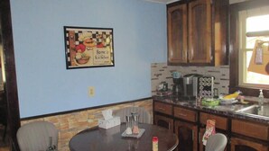 Eine Küche mit Holzausstattung, einer Kaffeemaschine, einer Mikrowelle und einem gerahmten Bild an der Wand.