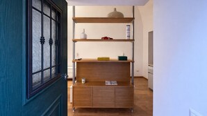 Ein Flur mit Holzschrank und Regalen, einer Tür mit Glasfenster und einer Deckenleuchte.
