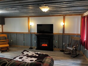 Una sala de estar acogedora con chimenea, televisor y dos lámparas de pie.