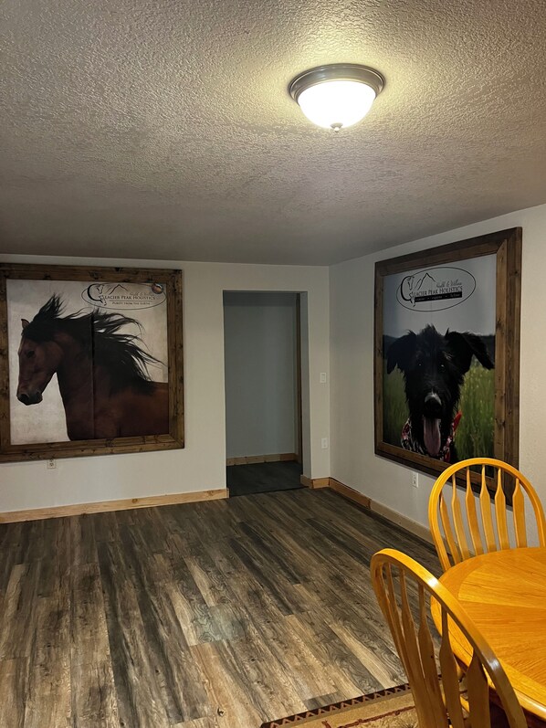 Ein Zimmer mit Holzböden, einem Esstisch mit Stühlen und zwei gerahmten Bildern an den Wänden.