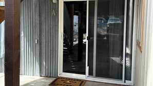 A covered porch with a sliding glass door leading to a garage. - Tobacco Riverwalk Condo - Eureka, MT (Eureka)