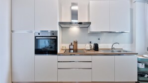 Une cuisine moderne avec des armoires blanches, des appareils en acier inoxydable et un plan de travail en bois.
