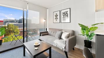 A modern living room with a sofa, a coffee table, and a balcony with outdoor furniture.