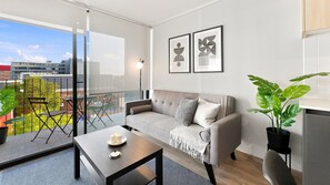 A modern living room with a sofa, a coffee table, and a balcony with outdoor furniture. - Oceana Suites Toesca (Santiago)