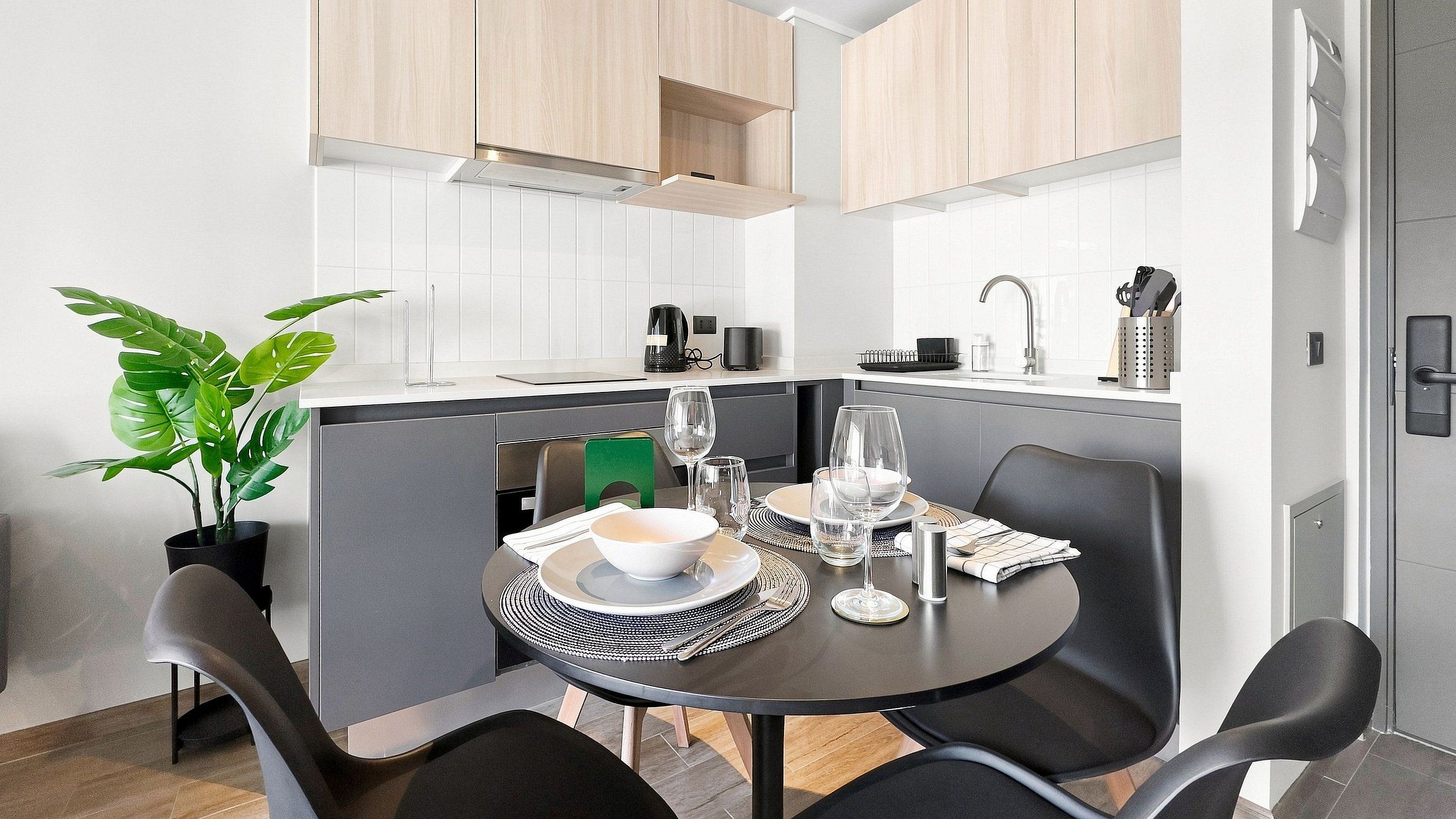 Una cucina compatta con mobili bianchi, una macchina da caffè e un lavandino.