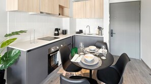 A compact kitchen with a dining area, including a stove, sink, and modern appliances. - Oceana Suites Toesca (Santiago)