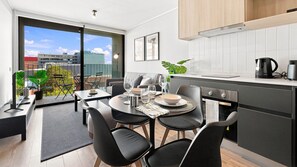 Una cocina moderna con comedor, vistas de la ciudad y un balcón con plantas.