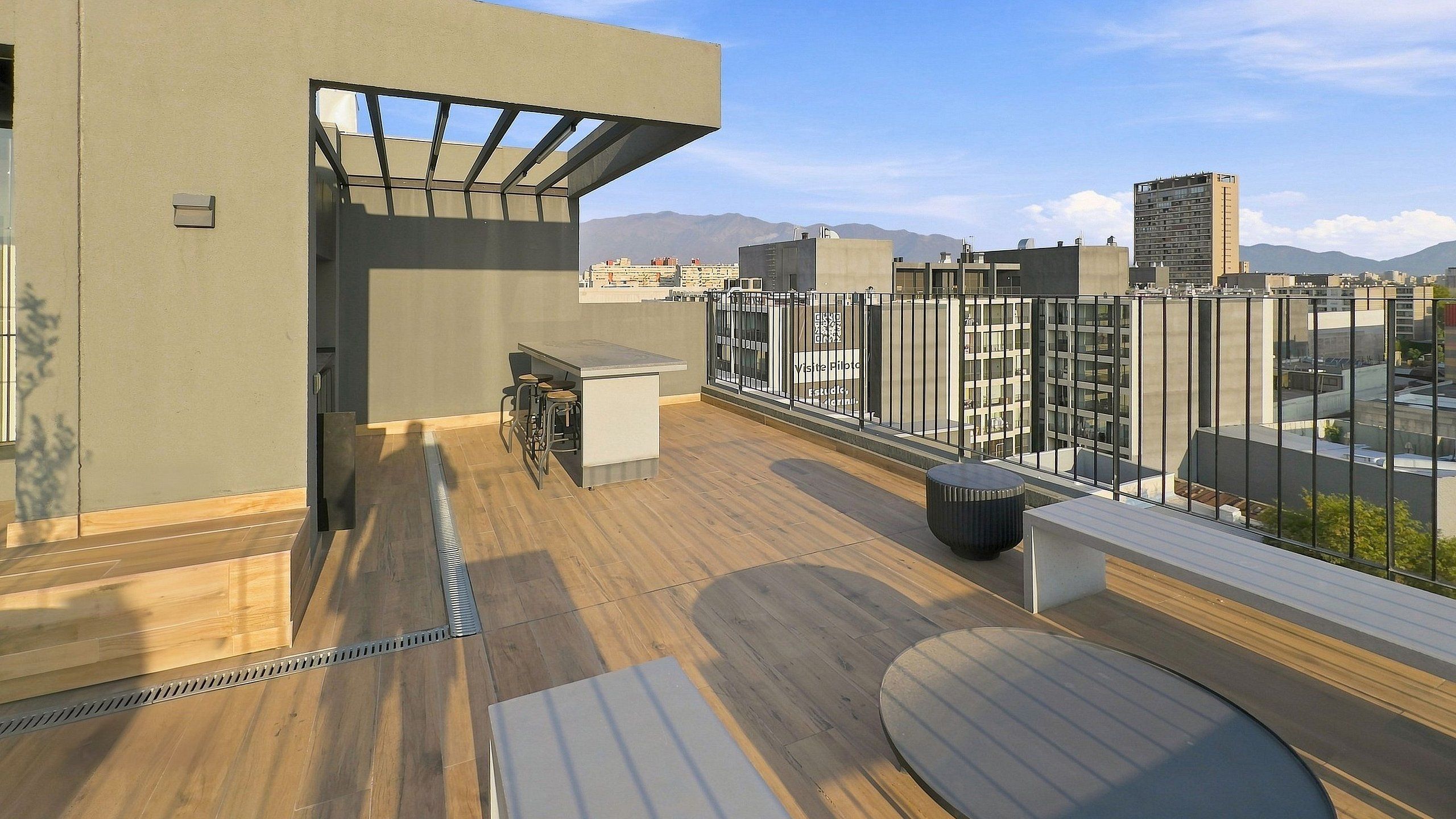 Una terraza en la azotea con suelo de madera, zona de bar y vistas a la ciudad.