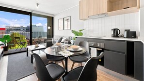A modern kitchen with a dining area, large windows, and a view of the city. - Oceana Suites Toesca (Santiago)