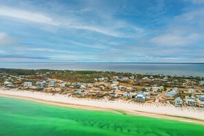 An aerial view of a coastal residential area with houses along the beachfront and a clear view of the ocean. - Gulf/Bay Views | Pet Friendly | Top Floor Lookout Deck | Delimara at the Cape⭐ (Cape San Blas)