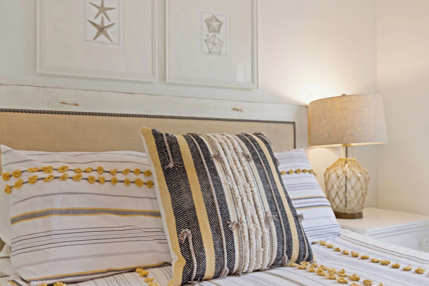 Un lit bien fait, agrémenté d’oreillers à rayures et d’une tête de lit décorative.