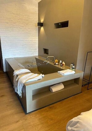 Une salle de bain moderne avec une grande baignoire, une étagère intégrée pour les serviettes et un luminaire fixé au mur.