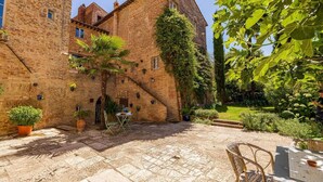 Une cour avec un bâtiment en briques, des plantes en pot et du mobilier d’extérieur.
