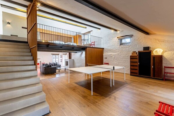 Une pièce spacieuse de style loft, avec un plafond haut, des murs en briques apparentes et une mezzanine.