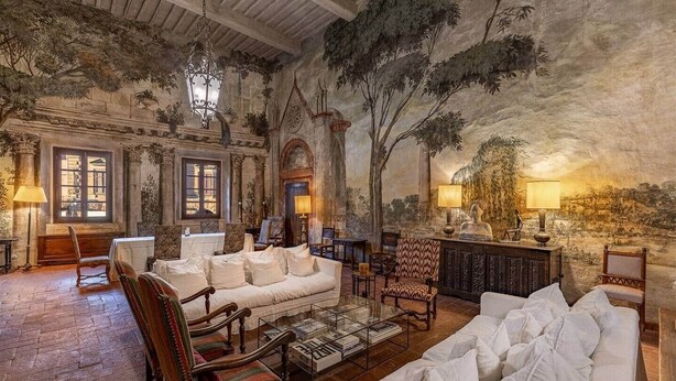 A spacious lounge with a high ceiling, ornate columns, and a mural depicting a natural landscape. There are several seating areas with white sofas and patterned chairs. - Donna Lavinia with indoor pool (Città della Pieve)