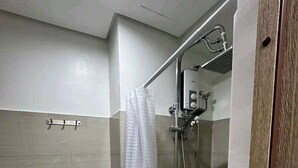 A small, modern bathroom with a toilet, shower, and a glass partition. - MOA Staycation Amenity view Escape @ Shell residence (Pasay City)