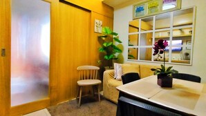 A compact living space with a wooden wardrobe, a small sofa, a dining table with chairs, and a potted plant. - MOA Staycation Amenity view Escape @ Shell residence (Pasay City)