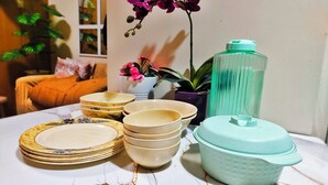 A table with stacked plates, bowls, and a green container. - MOA Staycation Amenity view Escape @ Shell residence (Pasay City)