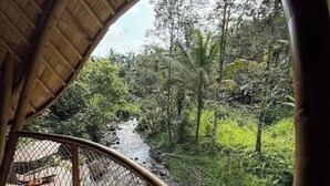Une structure en bambou offrant une vue sur une rivière et la végétation environnante.