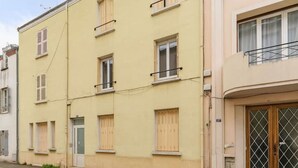 A row of two-story buildings with a flat facade, multiple windows, and a gated entrance. - Appartement calme et lumineux en centre ville (Vichy)