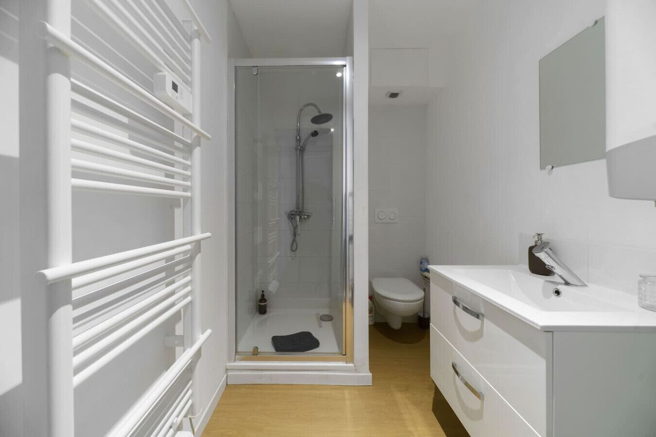 Un baño moderno con ducha acristalada, lavamanos blanco y retrete.