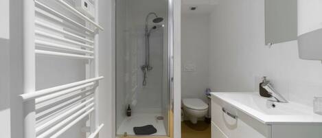 Un baño moderno con ducha acristalada, lavamanos blanco y retrete.